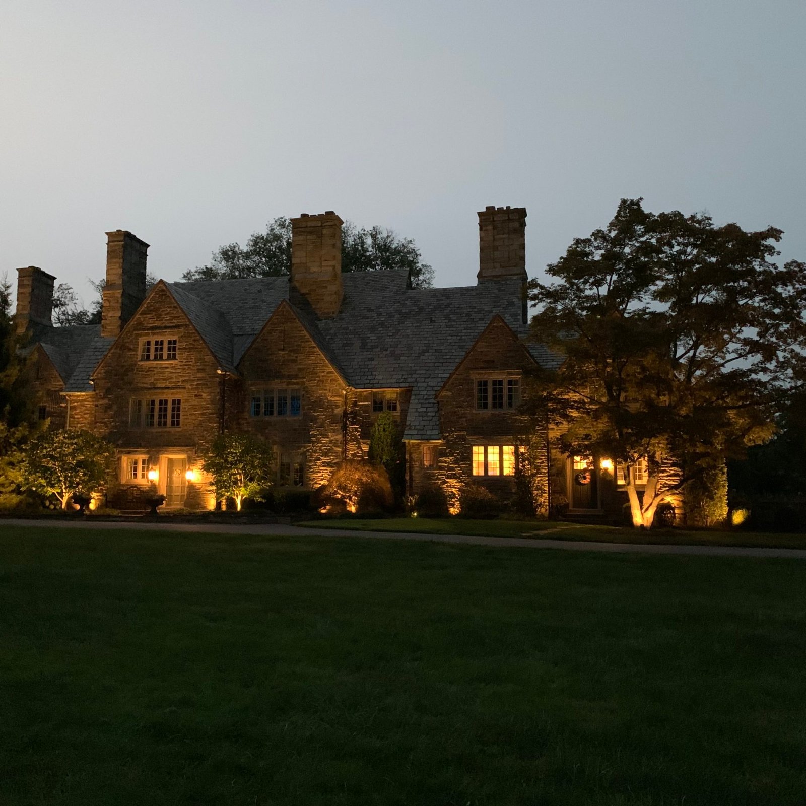 Stone manor with uplighting at dusk